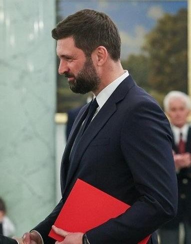 Nikodem Rachoń w kontekście swojej kariery zawodowej, przedstawiony w dynamicznej sytuacji, symbolizującej jego rolę w Biurze Polityki Międzynarodowej.