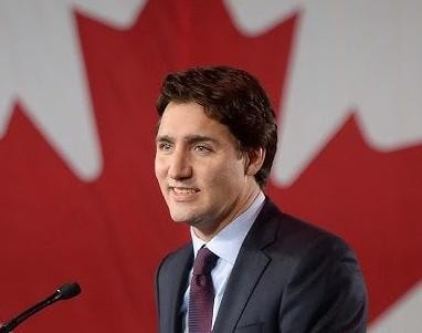 Justin Trudeau w interakcji z ludźmi w publicznym miejscu, uśmiechnięty i przystępny, co oddaje jego zaangażowanie w życie codzienne Kanadyjczyków.