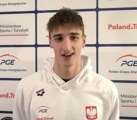 Wnętrze nowoczesnego basenu sportowego z trenującymi pływakami, symbolizujące profesjonalne środowisko treningowe.