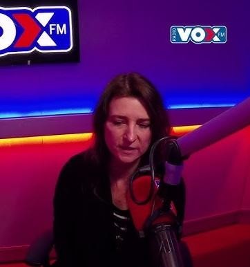 Renata Dąbkowska podczas występu na scenie, śpiewająca z mikrofonem, z dynamicznym oświetleniem i rozmytym tłem.