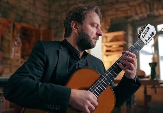 Marcin Dylla, wybitny gitarzysta klasyczny, podczas dynamicznego występu na żywo w prestiżowej sali koncertowej, skupiony na grze na gitarze klasycznej, z nastrojowym oświetleniem sceny.
