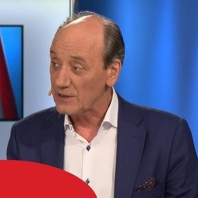 Dariusz Szpakowski w akcji, komentujący wydarzenie sportowe, z mikrofonem, symbolizujący jego wieloletnią pracę i pasję do komentowania.
