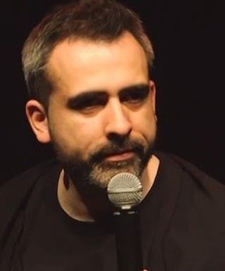 Zbliżenie na twarz Abelarda Gizy, polskiego komika, z zamyślonym i inteligentnym wyrazem.