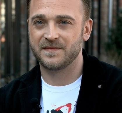 Mateusz Gessler w akcji w swojej restauracji, skupiony na przygotowaniu dania, z elementami kuchni w tle.