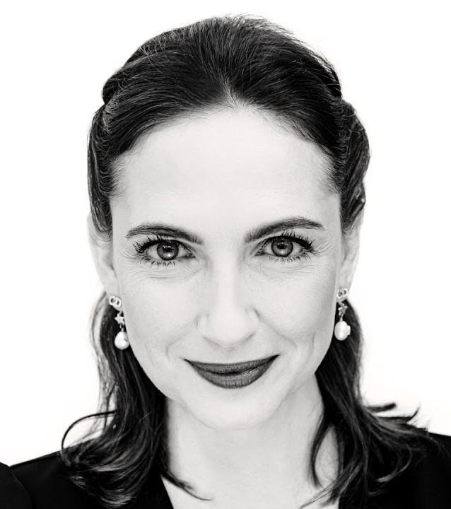 Anna Cieślak na planie filmowym, w kostiumie z jednej ze swoich ról, z profesjonalnym oświetleniem i rozmytym tłem sugerującym środowisko produkcji filmowej.