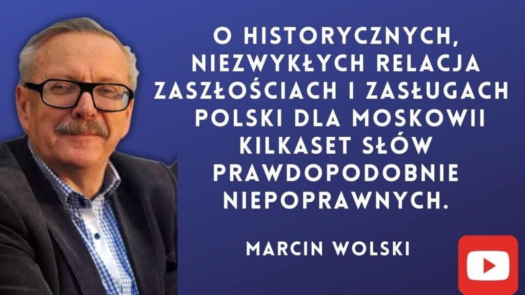 Marcin Wolski podczas audycji radiowej lub wystąpienia publicznego, ujęcie dynamiczne, z mikrofonem.