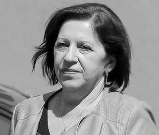 Czarno-białe zdjęcie kobiety o skupionym wyrazie twarzy, symbolizujące dyskrecję i zaangażowanie w pracę.