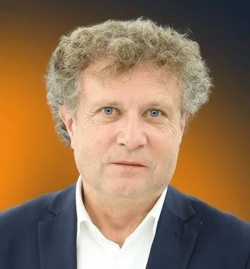 Jacek Karnowski uprawiający żeglarstwo na wodach Bałtyku, z zarysem Sopotu w tle, symbolizujący jego pasję do sportów wodnych.