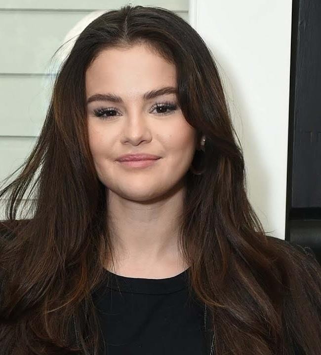 Selena Gomez na scenie z mikrofonem, symbolizująca jej sukces w karierze muzycznej.