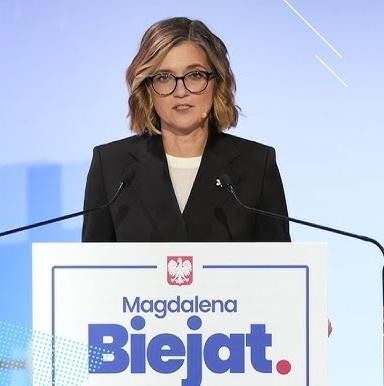 Magdalena Biejat podczas przemówienia na wiecu politycznym, energicznie gestykulująca, z widocznym zaangażowaniem w dialog społeczny.