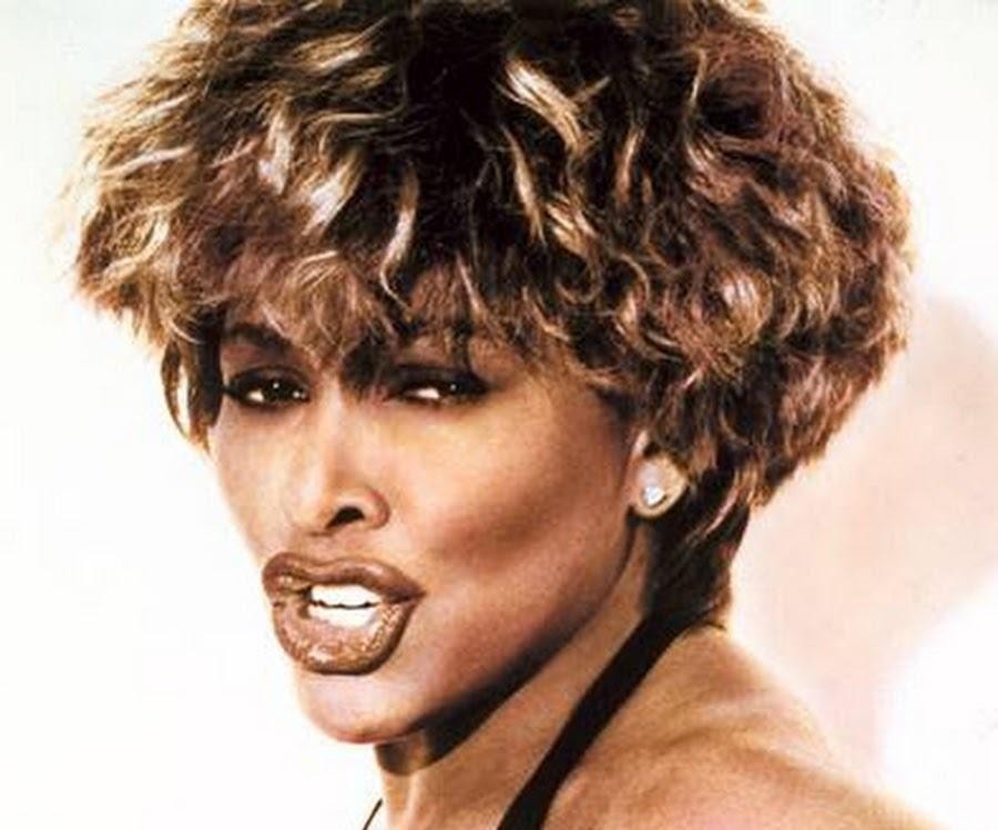 Tina Turner w późniejszych latach, siedząca spokojnie w eleganckim wnętrzu z widokiem na jezioro, uosabiająca spokój i mądrość.